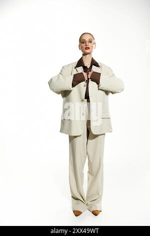 Femme en costume rayé crème ajuste le col, rouge à lèvres ajoute une touche de couleur. Banque D'Images