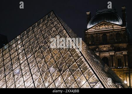 Vue nocturne de la pyramide du Louvre et du Palais historique du Louvre à Paris, en France, illuminé de lumières. Banque D'Images