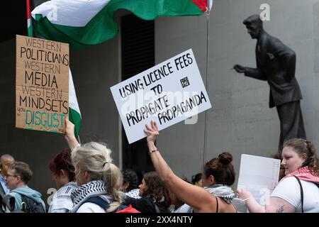 Londres, Royaume-Uni. 22 août 2024. Une foule tient des pancartes et des drapeaux, avec une statue de l'écrivain George Orwell par le sculpteur britannique Martin Jennings en arrière-plan, alors que des partisans de la Palestine protestent devant le siège de la BBC à Broadcasting House contre la couverture "biaisée" par les radiodiffuseurs publics de la guerre d'Israël contre Gaza, qui en est maintenant à son dixième mois. Crédit : Ron Fassbender/Alamy Live News Banque D'Images