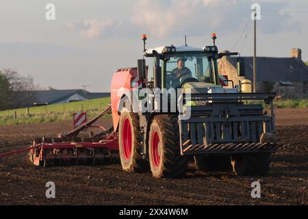 Vue de face d'un tracteur Fendt vert semant de l'orge avec un semoir universel Horsch sur des terres agricoles de l'Aberdeenshire sous un soleil de fin de soirée Banque D'Images