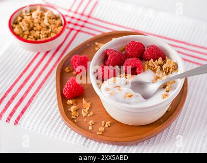 Yogourt nature à base de plantes garni de framboises fraîches et de granola ; vue en haut angle Banque D'Images