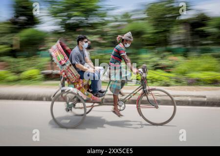 Les tireurs de pousse-pousse transportent des passagers sur la route de l'aéroport, dans la matinée à Dhaka, le lundi 11 juillet. Les pousse-pousse sont normalement interdits d'utilisation des routes, mais sont autorisés pendant le verrouillage actuel. Le Bangladesh traverse une vague de COVID-19, avec un record de 13768 cas le lundi 12 juillet. Le 14 juillet, les restrictions au confinement seront assouplies pendant neuf jours pour les célébrations d'Eid-ul-Azha. Les tireurs de pousse-pousse comptent parmi les travailleurs les moins bien payés au Bangladesh et ont ressenti les restrictions très durement. Au cours des efforts précédents sur le verrouillage, les tireurs de pousse-pousse où Banque D'Images