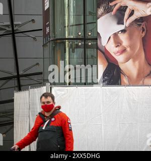 Un passager portant un masque facial se promo devant une annonce d'une femme dans un masque de sommeil à l'aéroport de Francfort, presque vide, lors du verrouillage causé par le virus COVID-19. Dans le monde entier, l'industrie du trafic aérien est fortement touchée par la baisse massive du trafic. Banque D'Images