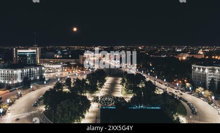 Panorama aérien nocturne de la place de la liberté dans la ville illuminée de Kharkiv avec la pleine lune Banque D'Images