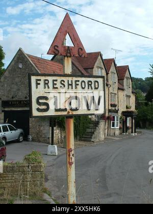 Ancien panneau routier près de l'auberge à Freshford , un village dans le nord du Somerset conseillant au trafic de ralentir. Banque D'Images