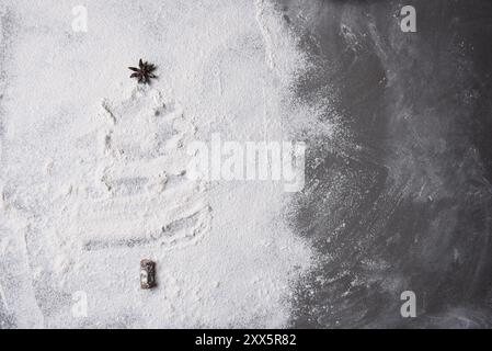 Forme d'arbre de Noël en farine étalée sur une plaque à pâtisserie. Le topper d'arbre est une gousse d'anis étoilé. Banque D'Images