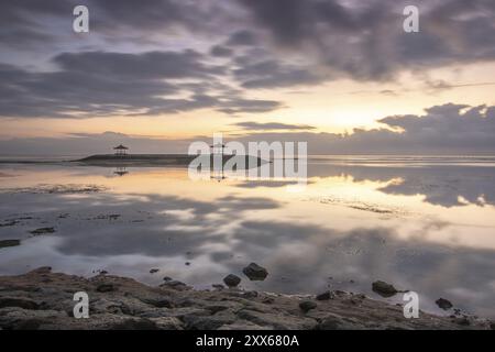 Beau paysage marin le matin. Plage de sable tropical avec brise-lames et reflet du ciel dans l'eau calme. Paysage matinal, pris à Sanur Banque D'Images