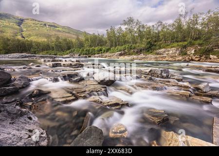 Abiskojakka, rivière dans le NP d'Abisko (nord de la Suède) . Longue exposition, roches, bouleau, nuages, ciel gris, mousse Banque D'Images