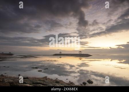 Beau paysage marin le matin. Plage de sable tropical avec brise-lames et reflet du ciel dans l'eau calme. Paysage matinal, pris à Sanur Banque D'Images