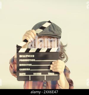 Kid holding clapper board dans les mains. Cinema concept. Retro style Banque D'Images