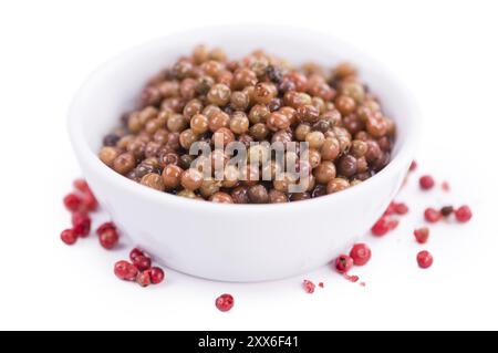 Grains de poivre rose conservés isolés sur fond blanc, mise au point sélective, gros plan Banque D'Images