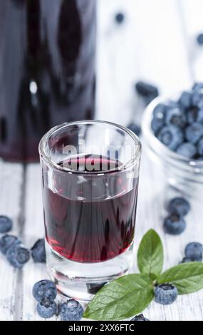 Liqueur de bleuets dans un verre (sur fond de bois) Banque D'Images