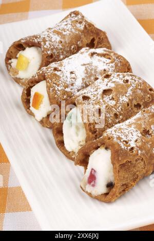 Gros plan de mini cannoli siciliens originaux sur une plaque blanche. Ces pâtisseries en forme de tube sont faites de coquilles frites remplies d'un mélange sucré de rico Banque D'Images