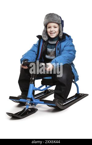 Petit garçon enfant souriant assis sur scooter des neiges ou jouet de motoneige blanc isolé Banque D'Images