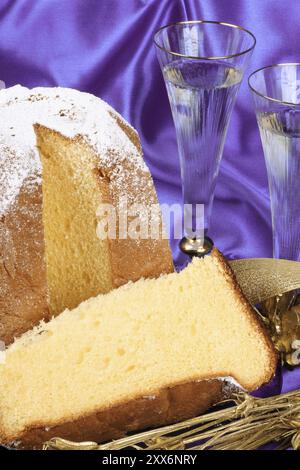 Composition de Noël avec Pandoro, le gâteau doré de Vérone, Italie et deux verres de spumante italienne sur un fond de tissu violet. Sélectif fo Banque D'Images