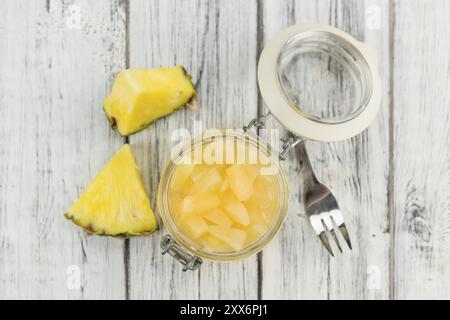 Ananas haché (conservé) en gros plan détaillé élevé sur une table en bois vintage, mise au point sélective Banque D'Images