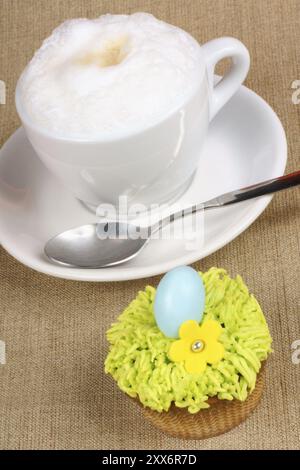 Cappuccino et petit gâteau de Pâques décoré de fleur de sucre et d'œuf en chocolat enrobé de sucre dur. Mise au point sélective Banque D'Images