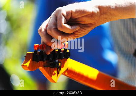 La main d'un homme sur la cheville d'une guitare Banque D'Images