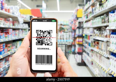 Gros plan d'une jeune femme faisant des achats dans un magasin, scannant le code QR, effectuant un paiement sans contact rapide et facile via smartphone pour ses achats chez self-che Banque D'Images