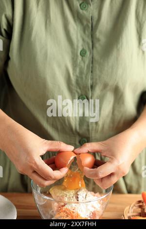 Main femelle cassant l'œuf de poulet dans le bol avec la pâte à farine Banque D'Images