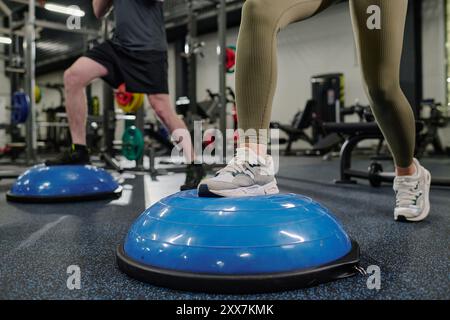 Jambes musclées féminines et masculines sur demi-balle pendant l'entraînement HIIT sur balle Banque D'Images