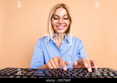 Photo de charmante femme positive porter une chemise bleue communiquant l'espace vide de l'appareil moderne isolé fond de couleur beige Banque D'Images