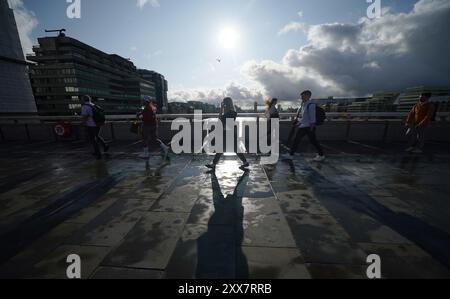 Les gens marchant dans des conditions venteuses sur le London Bridge alors que la tempête Lilian frappe le Royaume-Uni. Date de la photo : vendredi 23 août 2024. Banque D'Images