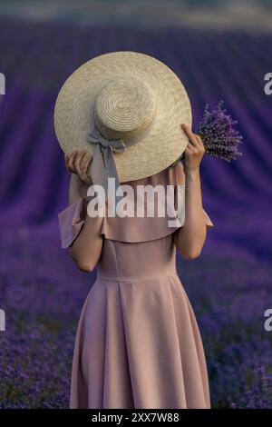 Une femme portant un chapeau de paille et tenant un bouquet de fleurs de lavande Banque D'Images