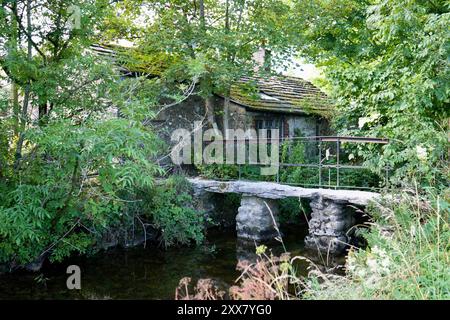 Pont de pierre rustique sur Malham Beck avec Malham Smithy derrière. Banque D'Images