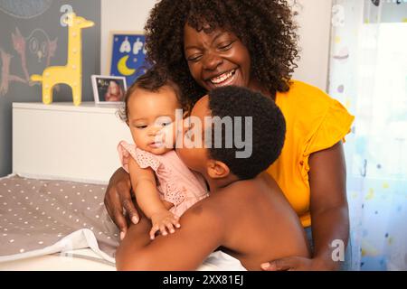 Famille heureuse partageant un moment tendre dans la pépinière Banque D'Images