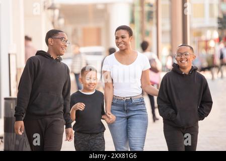 Femme afro-américaine marchant au centre-ville avec trois fils Banque D'Images