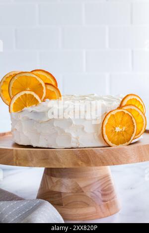 Gâteau blanc à l'orange givré avec des tranches d'orange séchées sur un support en bois Banque D'Images