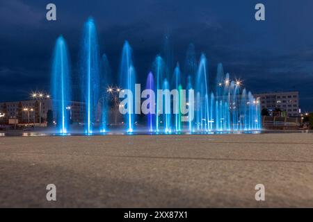 Fontaines illuminées en bleu sur la place de la ville. Banque D'Images