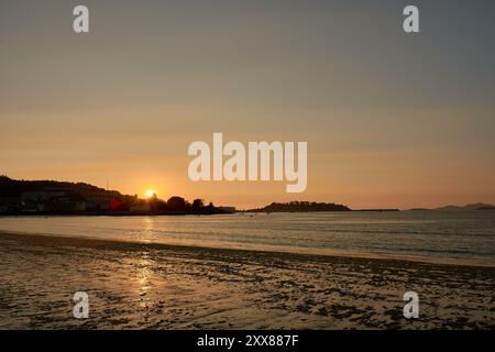 Coucher de soleil extraordinaire sur la plage de Ladeira à Bayona, où des teintes orange vibrantes peignent le ciel, créant une scène fascinante et inoubliable. Le soleil plonge Banque D'Images