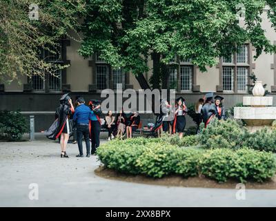 Bakou, Azerbaïdjan - 21 août 2023 : les diplômés se réunissent dans une cour luxuriante à Bakou, Azerbaïdjan, célébrant leurs réalisations en casquettes et robes, avec un bâtiment historique offrant une toile de fond pittoresque Banque D'Images