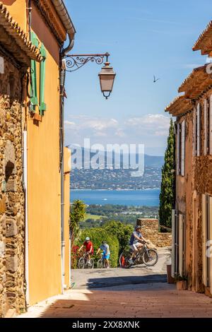 France, Var, Gassin, labellisés les plus beaux villages de France, ruelle dans le village avec cyclistes, le Golfe de Saint-Tropez en arrière-plan Banque D'Images