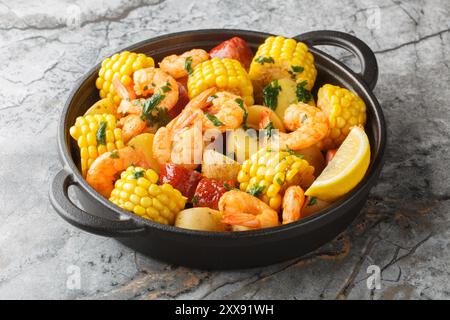 Tas de crevettes faire bouillir avec du maïs, des pommes de terre, des saucisses et des citrons en gros plan sur la table. Horizontal Banque D'Images