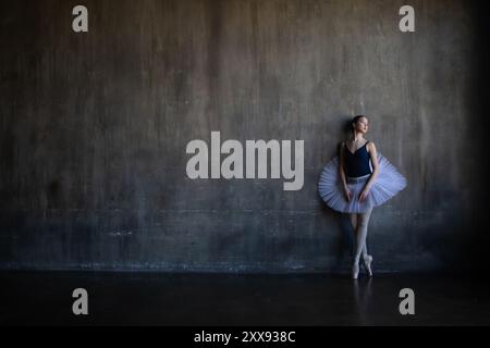 ballerine dans un tutu blanc se tient près du mur Banque D'Images