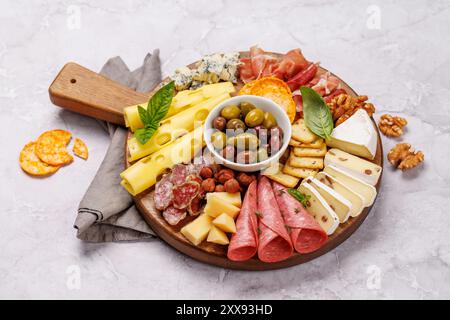 Une sélection de différents fromages et viandes disposés sur une planche de bois, parfaits pour une tartinade antipasto, présentant une variété de saveurs et de textures Banque D'Images