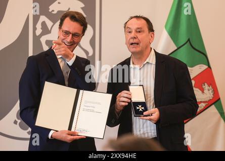 Duesseldorf, Allemagne. 23 août 2024. Le ministre-président Hendrik Wüst (à gauche, CDU) remet l'ordre du mérite d'État à l'artiste Jacques Tilly. Le célèbre constructeur de flotteurs du carnaval de Düsseldorf, Jacques Tilly, est l'un des onze nouveaux récipiendaires de l'ordre du mérite de l'État de Rhénanie-du-Nord-Westphalie. Crédit : Oliver Berg/dpa/Alamy Live News Banque D'Images