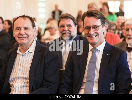 Duesseldorf, Allemagne. 23 août 2024. L’artiste Jacques Tilly (à gauche) est assis à côté du ministre-président Hendrik Wüst (CDU) avant la remise de l’ordre du mérite d’État à lui. Le célèbre constructeur de flotteurs du carnaval de Düsseldorf, Jacques Tilly, est l'un des onze nouveaux récipiendaires de l'ordre du mérite de l'État de Rhénanie-du-Nord-Westphalie. Crédit : Oliver Berg/dpa/Alamy Live News Banque D'Images