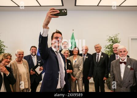 Duesseldorf, Allemagne. 23 août 2024. Le ministre-président Hendrik Wüst (M, CDU) prend un selfie après avoir remis l'ordre du mérite à de nombreux citoyens de Rhénanie du Nord-Westphalie. Crédit : Oliver Berg/dpa/Alamy Live News Banque D'Images