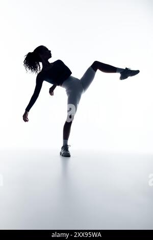 Une jeune femme avec une construction puissante effectue un étirement dynamique des jambes, démontrant son athlétisme et sa force. Banque D'Images