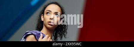 Une jeune femme afro-américaine regarde vers le haut, rayonnant de force et de confiance dans un cadre de studio. Banque D'Images