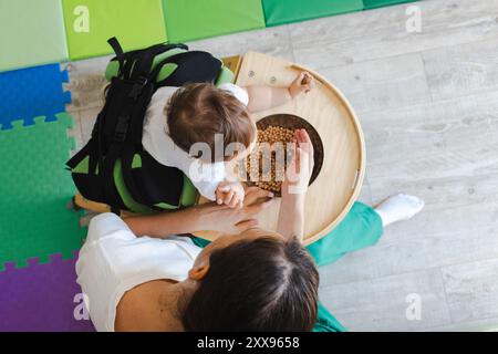 Vue de dessus de la séance de rééducation sensorielle et physique d'un petit enfant mâle debout dans un verticalisateur avec ergothérapeute Banque D'Images