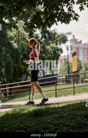 Une jeune femme atteinte de vitiligo marche dans un parc, portant un crop top rose et un short de sport noir. Banque D'Images