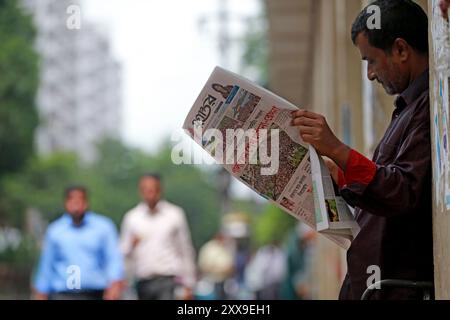 Le lendemain de la démission de Sheikh Hasina, un homme regarde les journaux de Dhaka, Bangladesh, le 06 août 2024. Banque D'Images