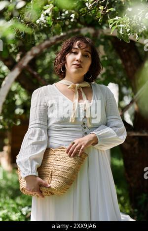 Une jeune femme vêtue d'une robe blanche et d'un chapeau de paille profite d'une journée d'été dans un jardin. Banque D'Images