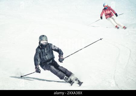 Gros plan vue de face homme sur le skis mouvement de gel de descente. Vacances d'hiver actives, ski de descente en journée ensoleillée. Image lumineuse couple homme femme skieurs Banque D'Images