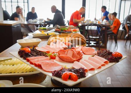 Groupe d'hommes caucasiens amis, la famille assis dans le restaurant de l'hôtel manger prendre le petit déjeuner avant de skier en vacances dans les montagnes enneigées Banque D'Images